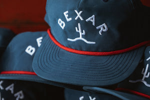 Blue Bexar Cap front view on a wooden table, showcasing the Bexar Goods logo patch