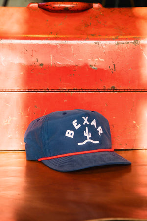 Blue Bexar Cap front view on a wooden table, showcasing the Bexar Goods logo patch